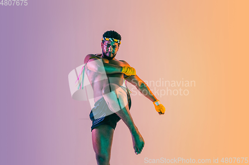 Image of Muay thai. Young man exercising thai boxing on gradient background