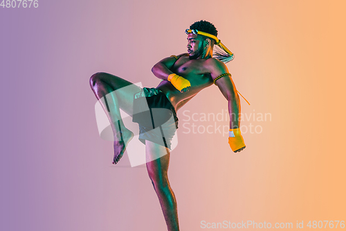 Image of Muay thai. Young man exercising thai boxing on gradient background