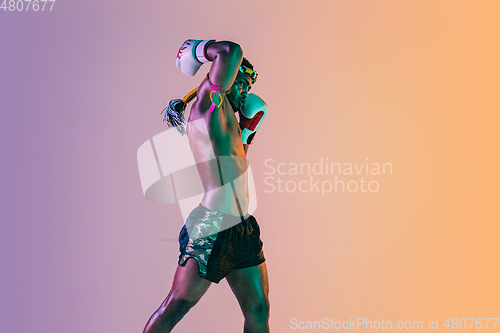 Image of Muay thai. Young man exercising thai boxing on gradient background