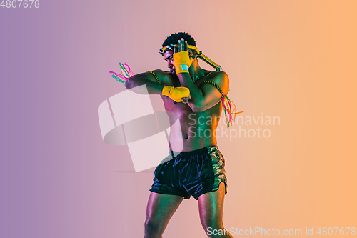 Image of Muay thai. Young man exercising thai boxing on gradient background