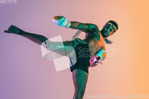 Image of Muay thai. Young man exercising thai boxing on gradient background