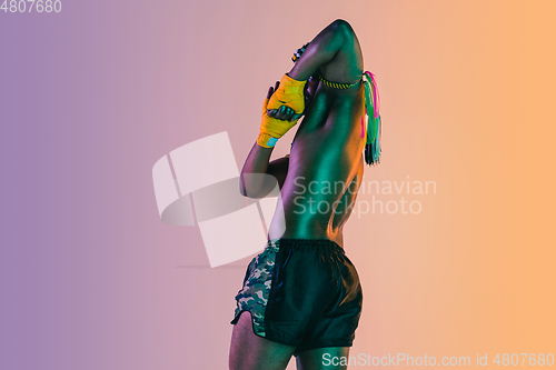 Image of Muay thai. Young man exercising thai boxing on gradient background