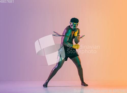 Image of Muay thai. Young man exercising thai boxing on gradient background