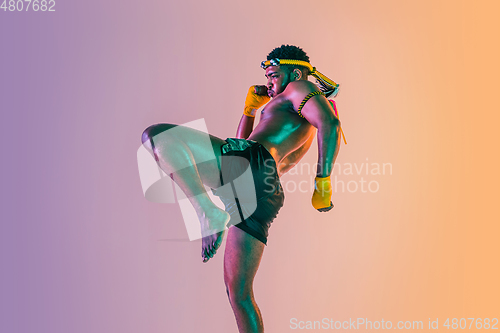 Image of Muay thai. Young man exercising thai boxing on gradient background