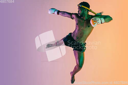 Image of Muay thai. Young man exercising thai boxing on gradient background