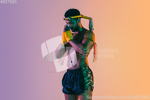 Image of Muay thai. Young man exercising thai boxing on gradient background