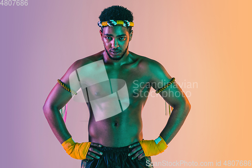 Image of Muay thai. Young man exercising thai boxing on gradient background