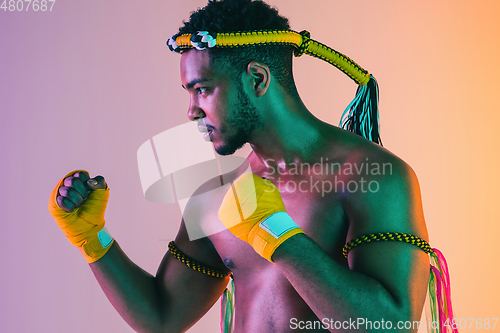 Image of Muay thai. Young man exercising thai boxing on gradient background