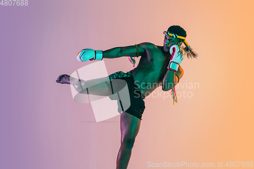 Image of Muay thai. Young man exercising thai boxing on gradient background