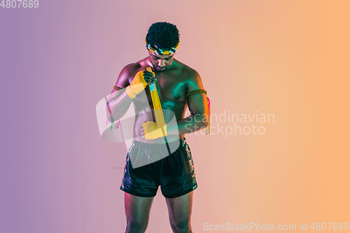 Image of Muay thai. Young man exercising thai boxing on gradient background