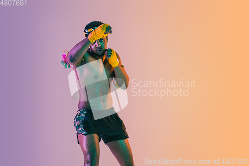 Image of Muay thai. Young man exercising thai boxing on gradient background