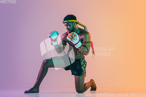 Image of Muay thai. Young man exercising thai boxing on gradient background