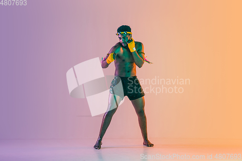 Image of Muay thai. Young man exercising thai boxing on gradient background