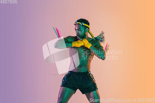 Image of Muay thai. Young man exercising thai boxing on gradient background