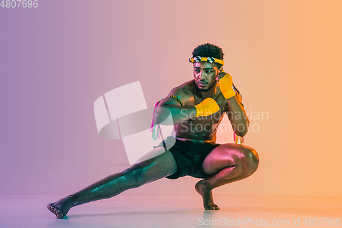 Image of Muay thai. Young man exercising thai boxing on gradient background