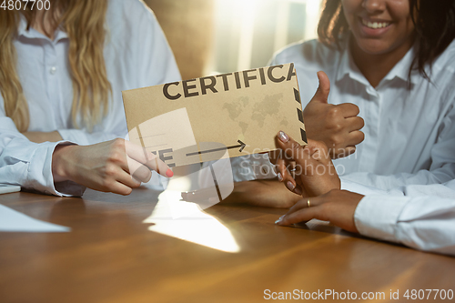 Image of Close up of african-american and caucasian human\'s hands holding certificate or inviting card