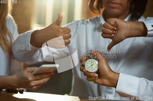 Image of Close up of african-american and caucasian human\'s hands pinpointing time