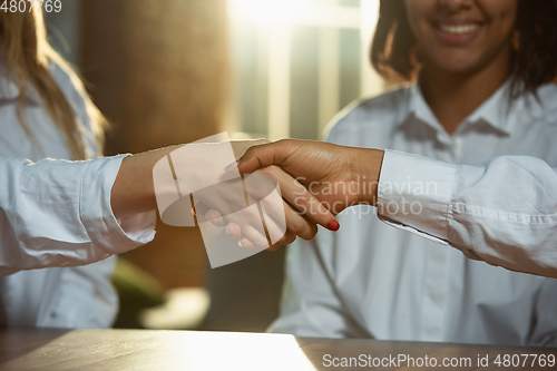 Image of Close up of african-american and caucasian human\'s hands holding on wooden table