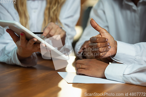 Image of Close up of african-american human\'s hands using tablet on wooden table