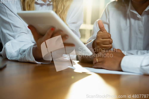 Image of Close up of african-american human\'s hands using tablet on wooden table