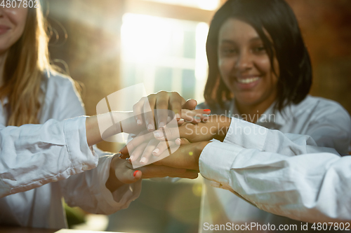 Image of Close up of african-american and caucasian human\'s hands holding on wooden table