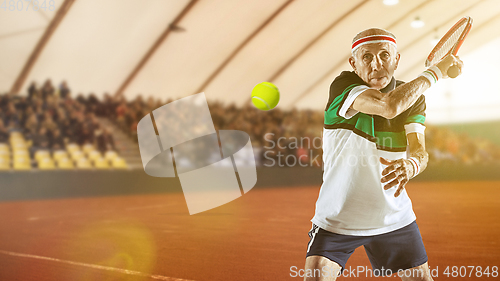 Image of Senior man playing tennis in sportwear on stadium