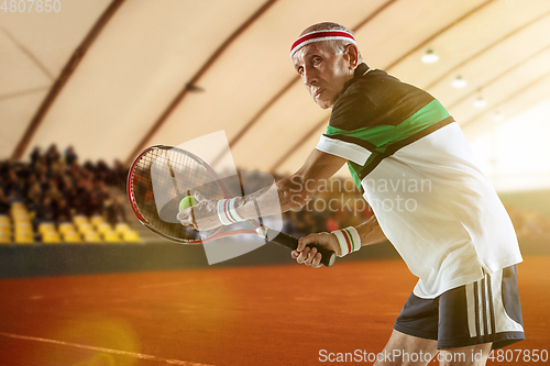 Image of Senior man playing tennis in sportwear on stadium