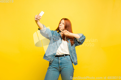 Image of Caucasian woman\'s portrait isolated on yellow studio background, follower be like