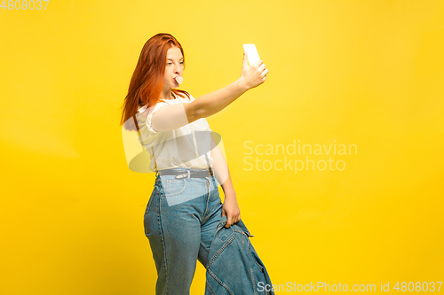 Image of Caucasian woman\'s portrait isolated on yellow studio background, follower be like