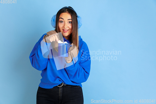 Image of Caucasian woman\'s portrait isolated on blue studio background, winter theme