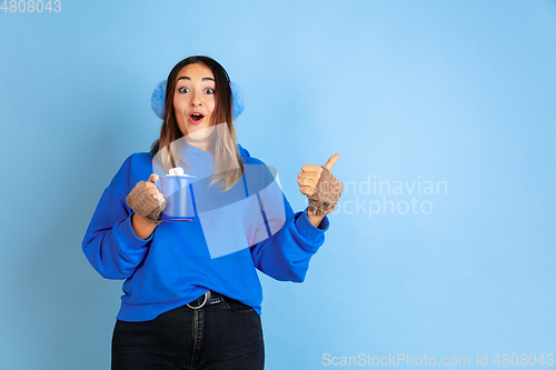 Image of Caucasian woman\'s portrait isolated on blue studio background, winter theme