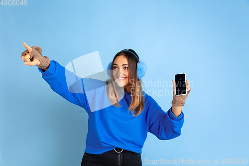 Image of Caucasian woman\'s portrait isolated on blue studio background, winter theme