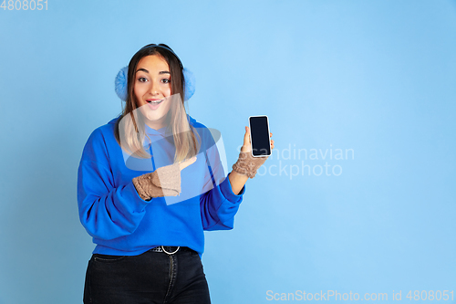 Image of Caucasian woman\'s portrait isolated on blue studio background, winter theme