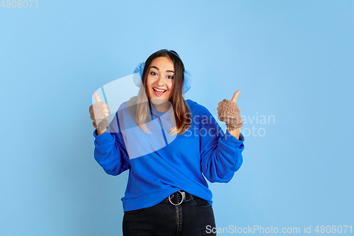Image of Caucasian woman\'s portrait isolated on blue studio background, winter theme