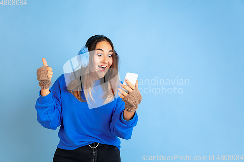 Image of Caucasian woman\'s portrait isolated on blue studio background, winter theme