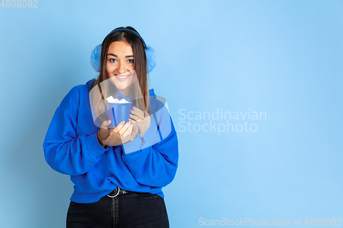 Image of Caucasian woman\'s portrait isolated on blue studio background, winter theme