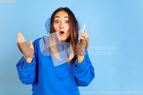 Image of Caucasian woman\'s portrait isolated on blue studio background, winter theme