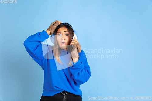 Image of Caucasian woman\'s portrait isolated on blue studio background, winter theme