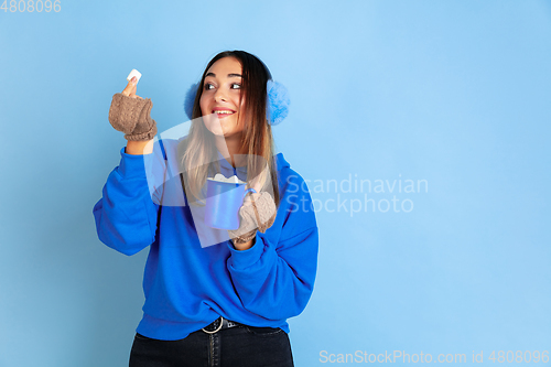 Image of Caucasian woman\'s portrait isolated on blue studio background, winter theme