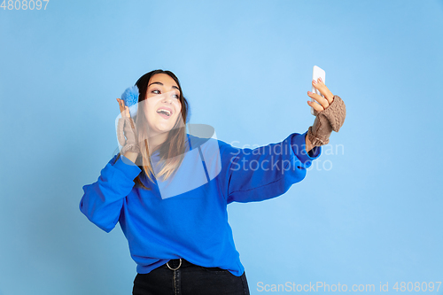 Image of Caucasian woman\'s portrait isolated on blue studio background, winter theme