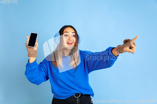 Image of Caucasian woman\'s portrait isolated on blue studio background, winter theme