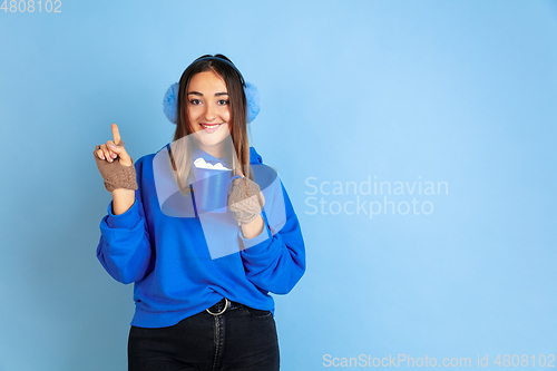 Image of Caucasian woman\'s portrait isolated on blue studio background, winter theme