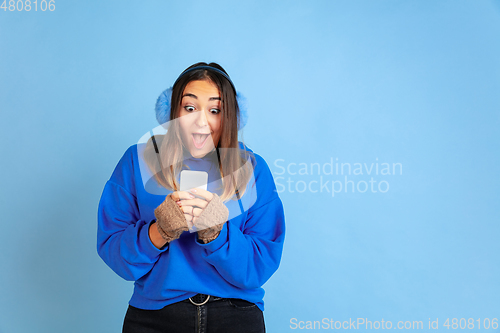 Image of Caucasian woman\'s portrait isolated on blue studio background, winter theme