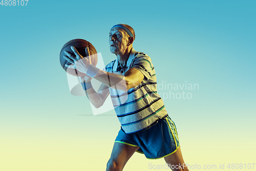 Image of Senior man playing basketball in sportwear on gradient background and neon light