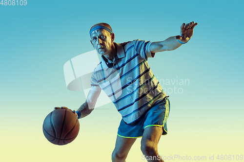 Image of Senior man playing basketball in sportwear on gradient background and neon light