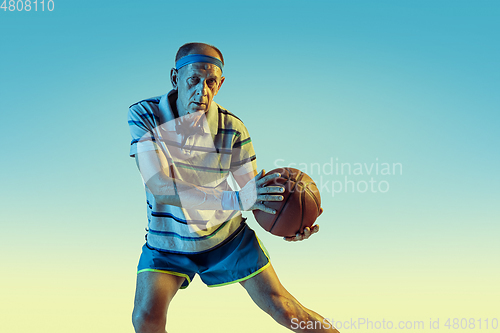 Image of Senior man playing basketball in sportwear on gradient background and neon light