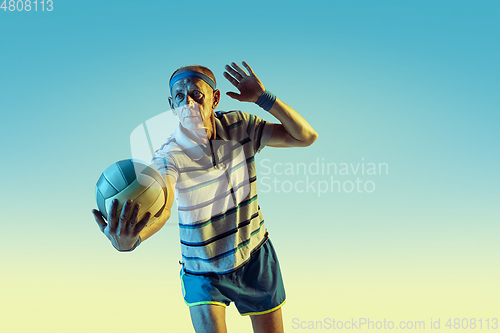 Image of Senior man playing volleyball in sportwear on gradient background and neon light