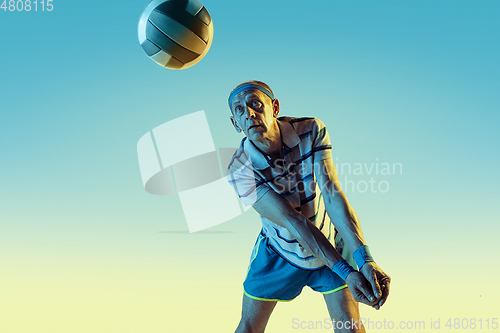 Image of Senior man playing volleyball in sportwear on gradient background and neon light