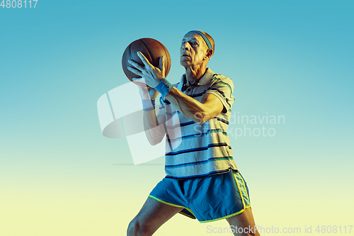 Image of Senior man playing basketball in sportwear on gradient background and neon light