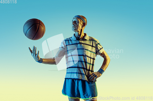 Image of Senior man playing basketball in sportwear on gradient background and neon light